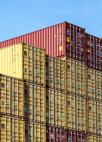 Colorful stacked cargo containers in Hamburg port under a clear blue sky.